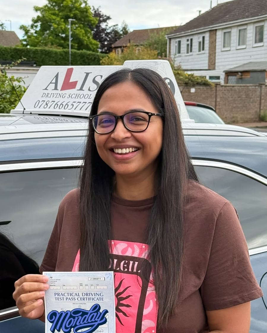 A pupil holding their practical driving test pass certificate beside Ali's car in King's Lynn.