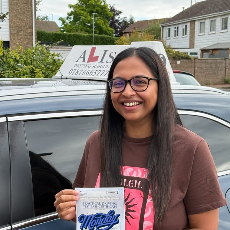 A pupil holding their practical driving test pass certificate beside Ali's car in King's Lynn.