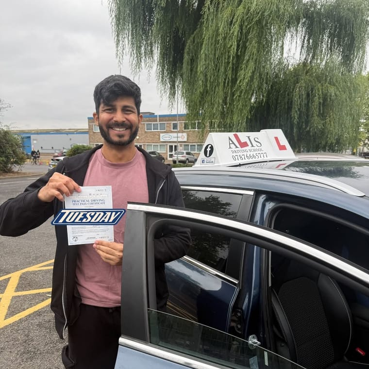 A pupil holding their practical driving test pass certificate beside Ali's car in King's Lynn.